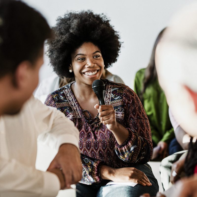 Cheerful woman speaking on a microphone in a workshop